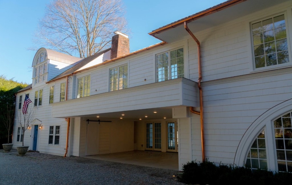 Completed white shingle home with copper gutters and covered entry