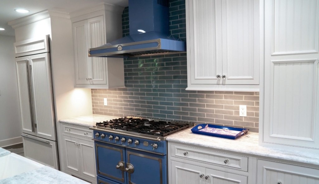 Kitchen remodel with blue range, white beadboard cabinets, and subway tile