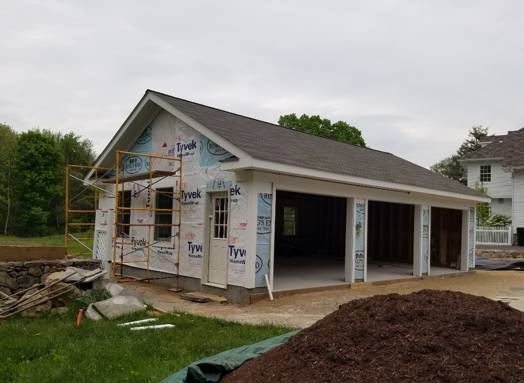 Garage outbuilding under construction with Tyvek wrap, windows, and scaffolding